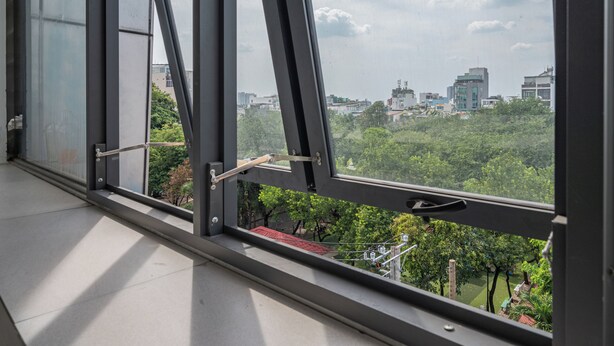 Vista desde una ventana con marcos de metal y una panorámica de la ciudad con edificios y áreas verdes.