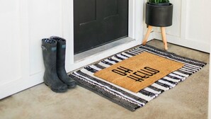 A black door with a wreath, a potted plant, and a doormat. - Cozy Country Farmhouse (Burley)