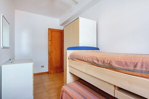 A bedroom with a bunk bed, a wardrobe, and a desk.