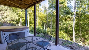 Une terrasse extérieure dotée d’une pergola en bois, d’une table ronde en métal et de deux chaises.