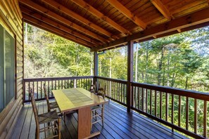 Une terrasse en bois avec une table et des chaises, donnant sur une zone boisée.