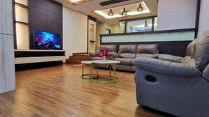Una sala de estar moderna con un televisor de pantalla plana, un sofá gris y una mesa de centro.