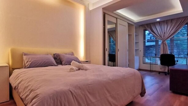 Un dormitorio con una cama grande, una mesita de noche, una silla y vistas al exterior a través de una ventana.
