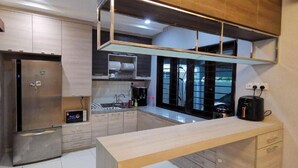Una cocina moderna con un refrigerador de acero inoxidable, un horno empotrado y una cafetera.