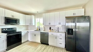 Une cuisine moderne avec des armoires blanches, des appareils en acier inoxydable et un plancher en bois.