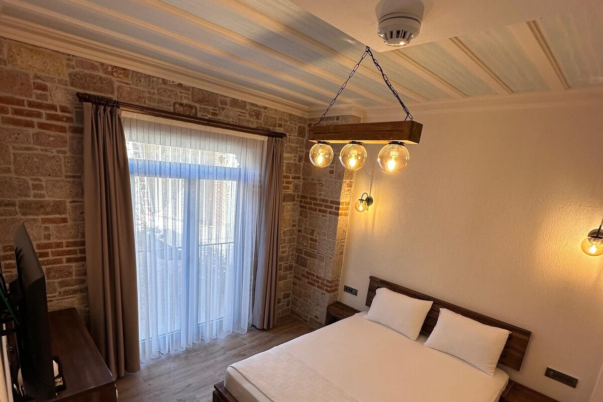 Un dormitorio con una cama grande, un banco de madera, un televisor y una pared de ladrillo.