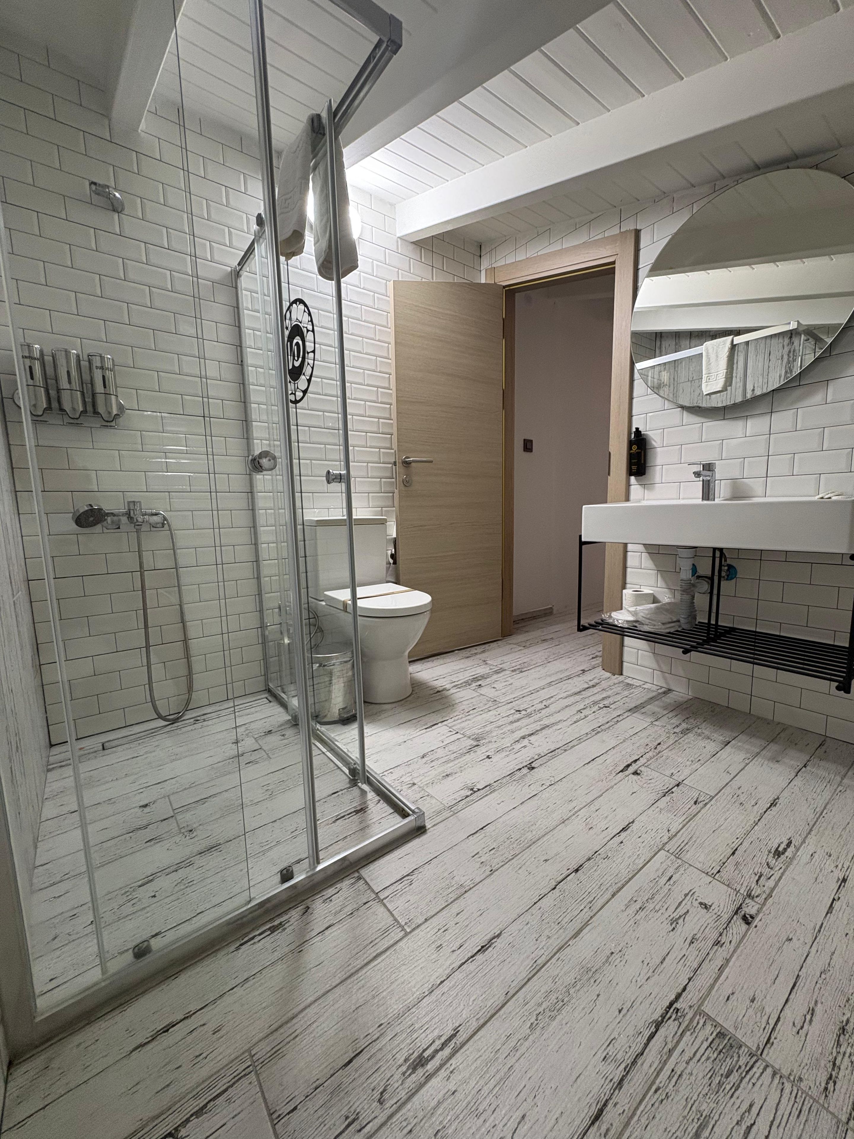 Un baño con cabina de ducha de vidrio, inodoro y lavamanos con toallero.