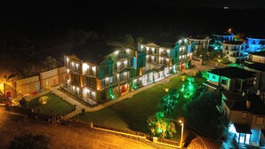 A multi-story hotel with illuminated balconies and a well-maintained lawn. - Cunda Nisa Otel (Ayvalik)