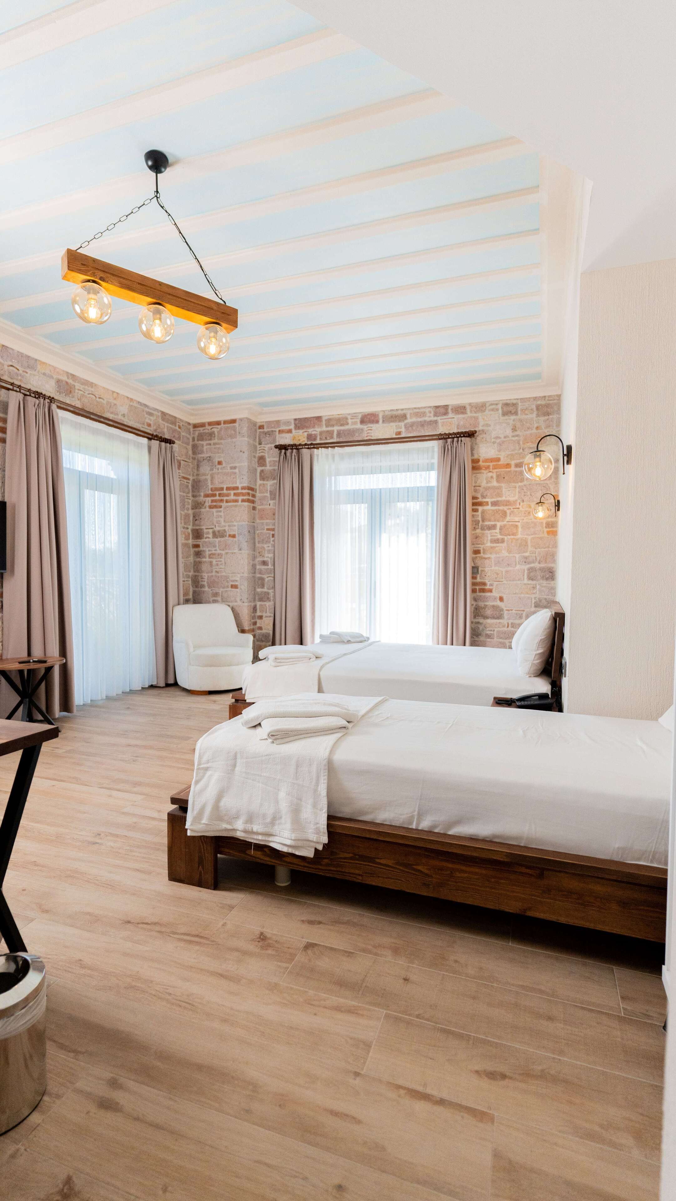 A modern bedroom with a brick wall, a wooden bed frame, and a hanging light fixture.