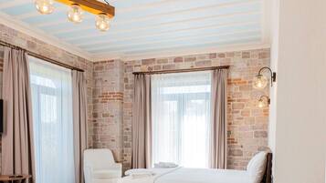 A modern bedroom with a brick wall, a wooden bed frame, and a hanging light fixture.