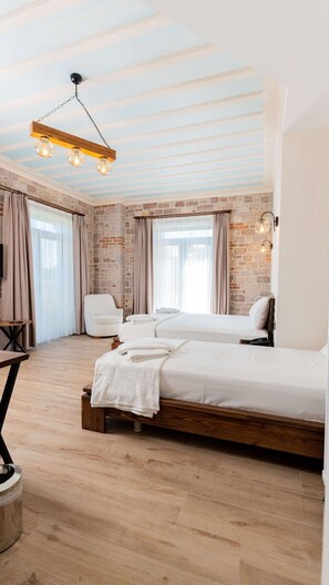 A modern bedroom with a brick wall, a wooden bed frame, and a hanging light fixture. - Cunda Nisa Otel (Ayvalik)
