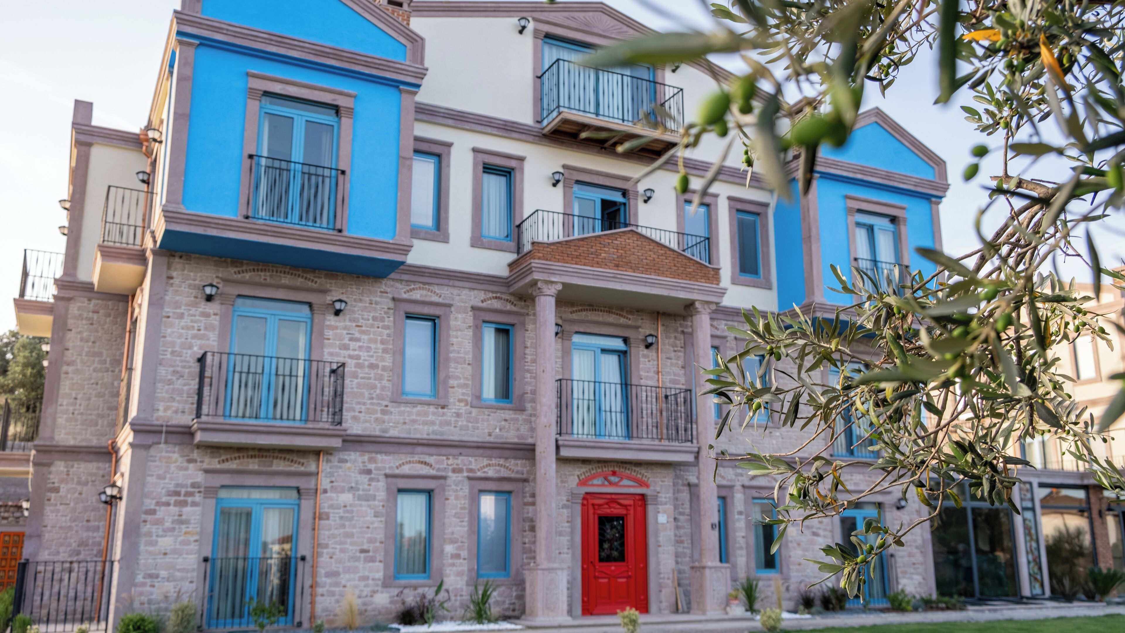 A multi-story building with a red door, blue windows, and balconies.