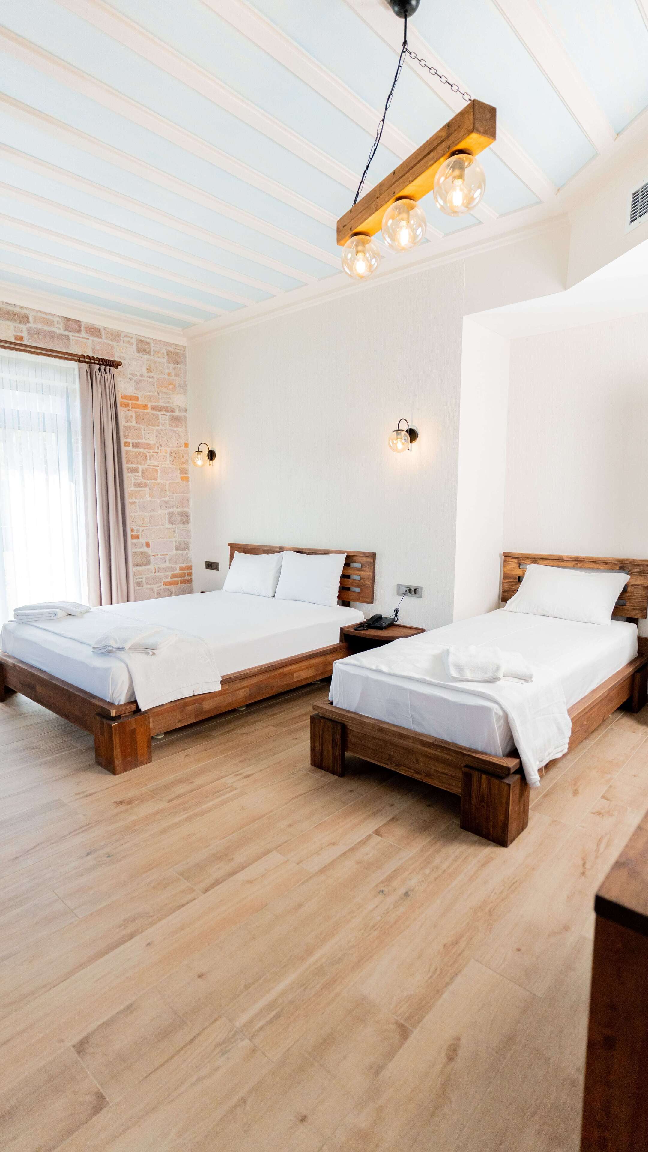 A hotel room with two wooden beds, a brick wall, and a wooden ceiling.