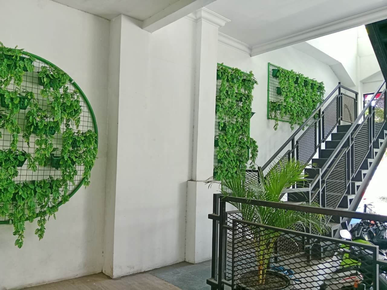 A staircase with a metal railing, surrounded by walls adorned with green leafy wall art.