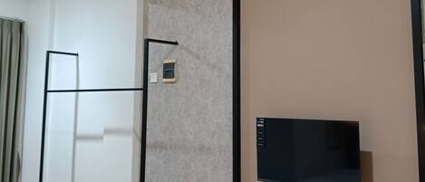 A room with a flat-screen TV mounted on a brown wall, a wooden bench, and a standing desk.