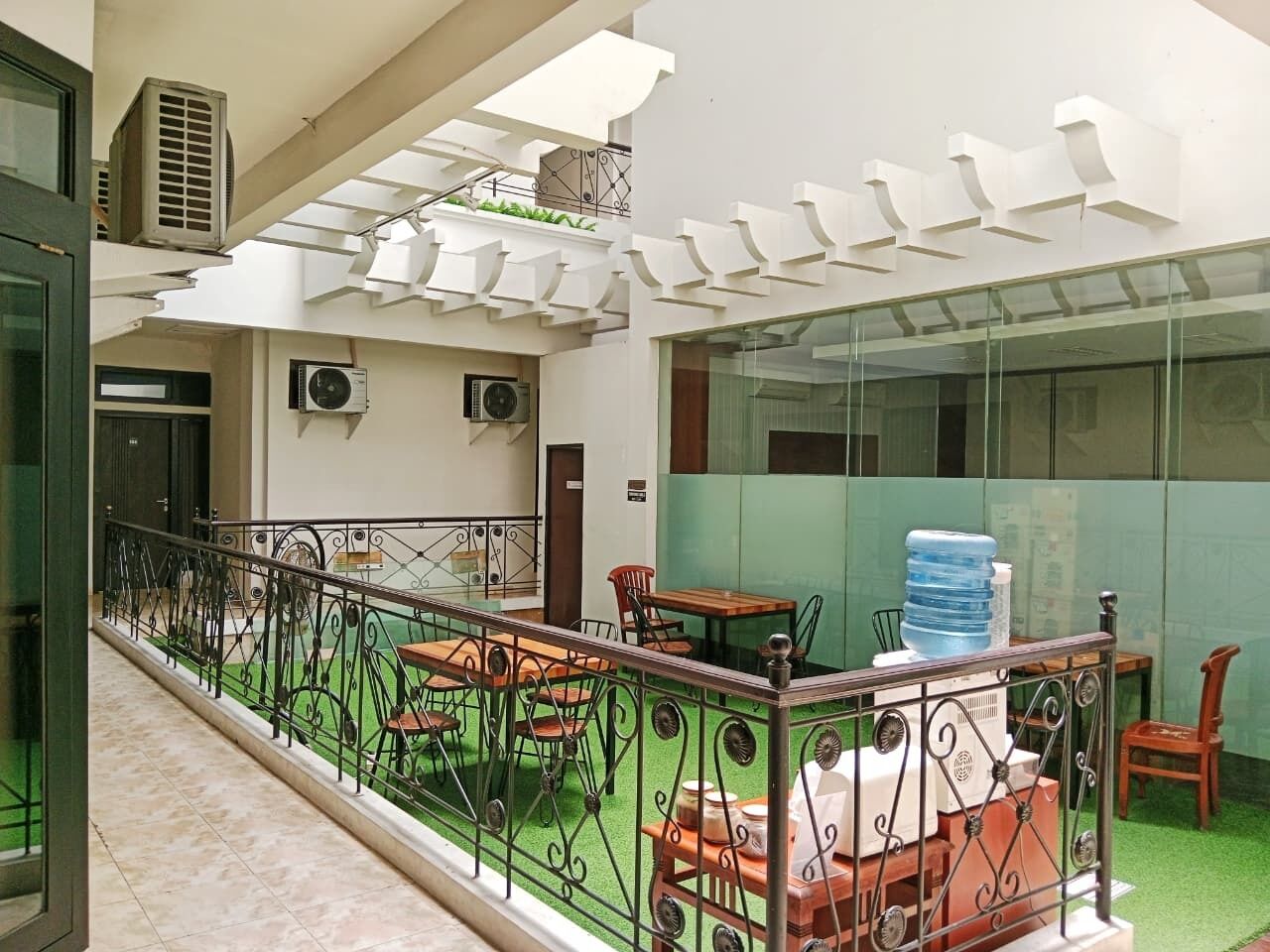 Eine Dachterrasse mit Außenmöbeln, Klimaanlagen und Wasserspender.