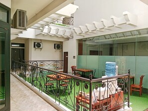 A rooftop terrace with outdoor seating, air conditioning units, and a water dispenser. - Hotel Nara Arta Syariah (Surabaya)
