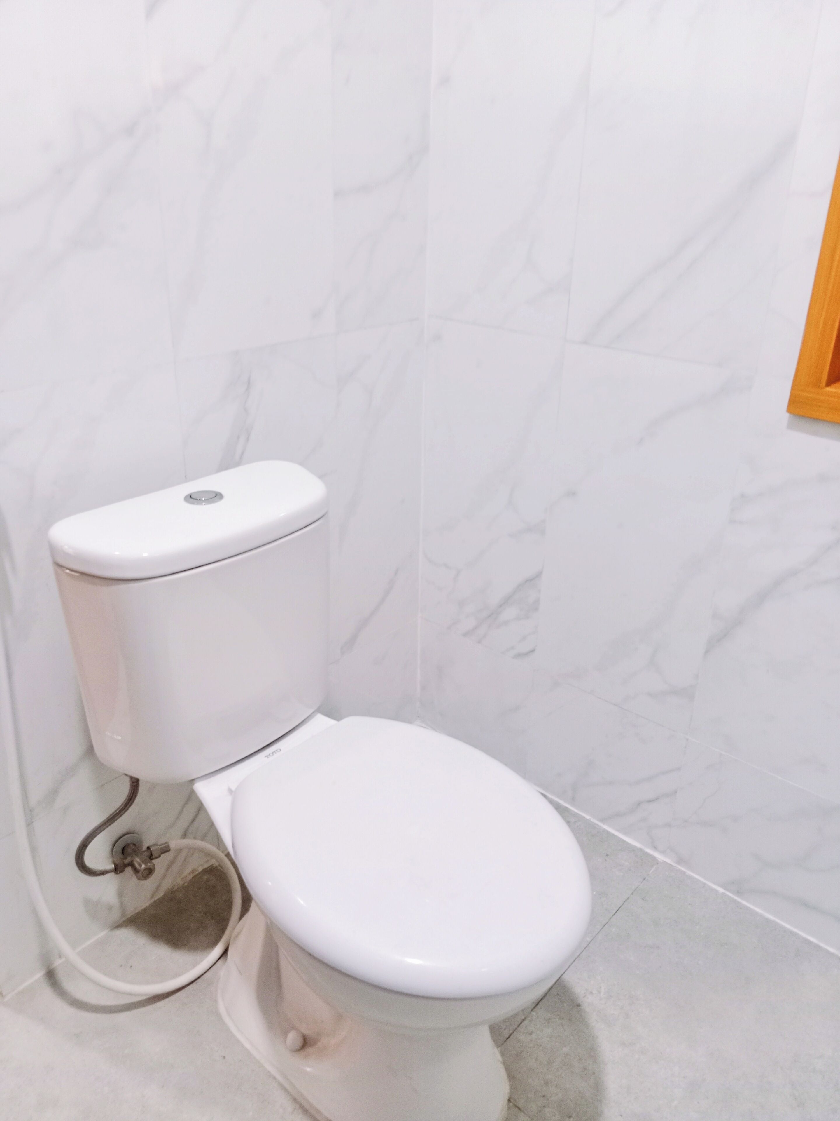 Een wit toilet met een achtergrond van een wand in marmerlook.