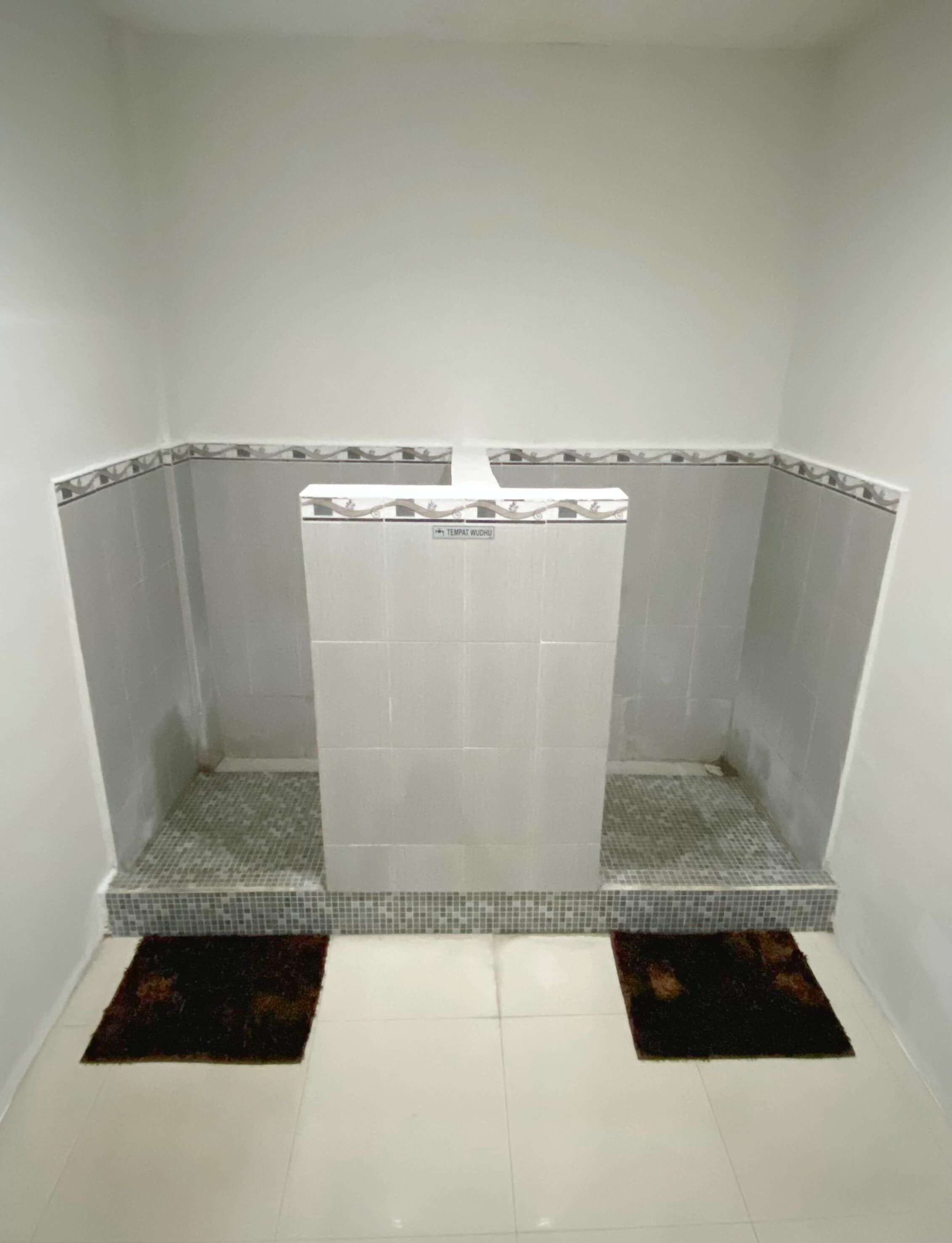 A small, enclosed shower area with tiled walls and floor, a white shower curtain, and a small tiled ledge.