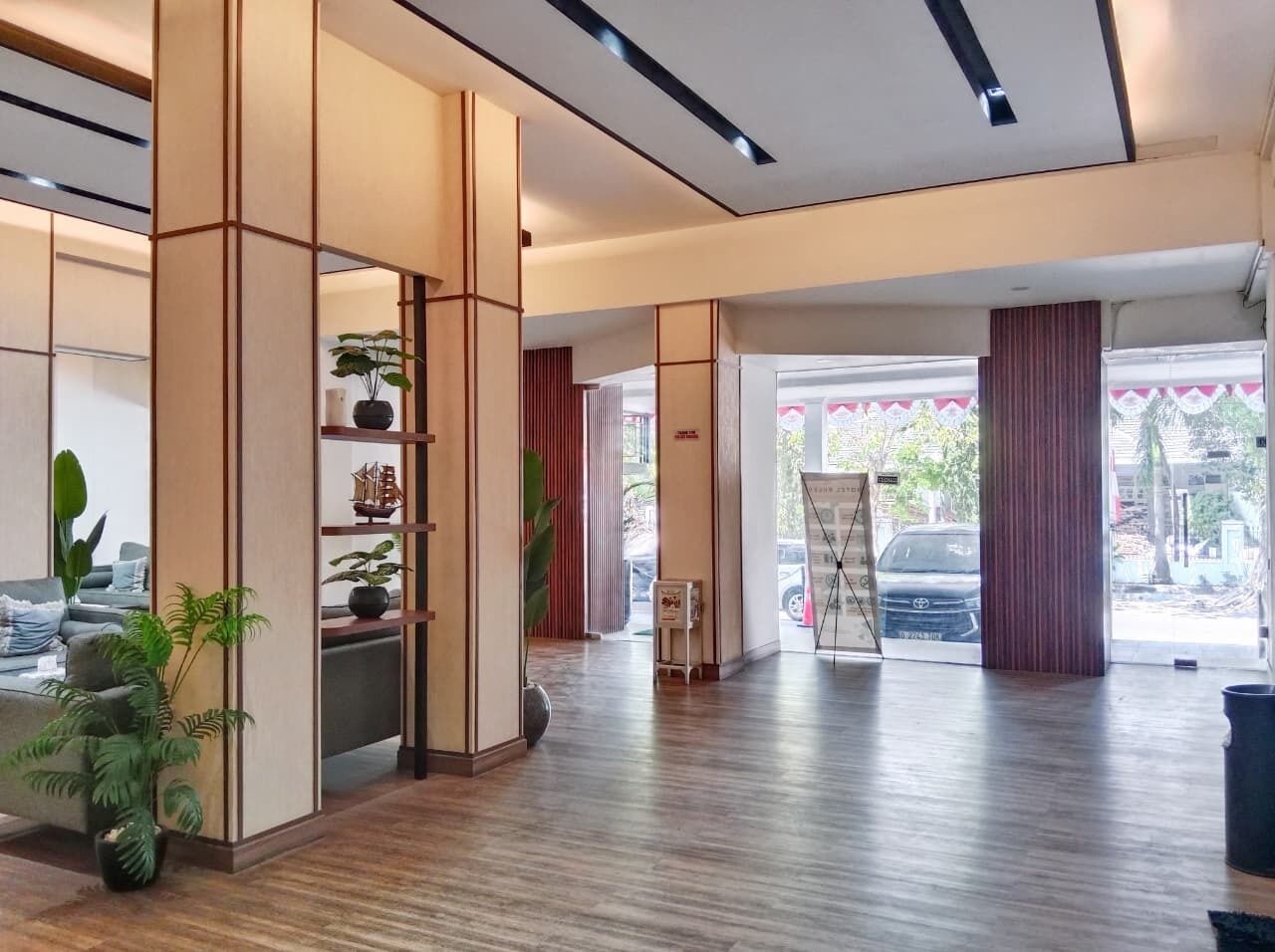 A spacious lobby with a wooden floor, a reception desk, and a large window offering a view of the outside.
