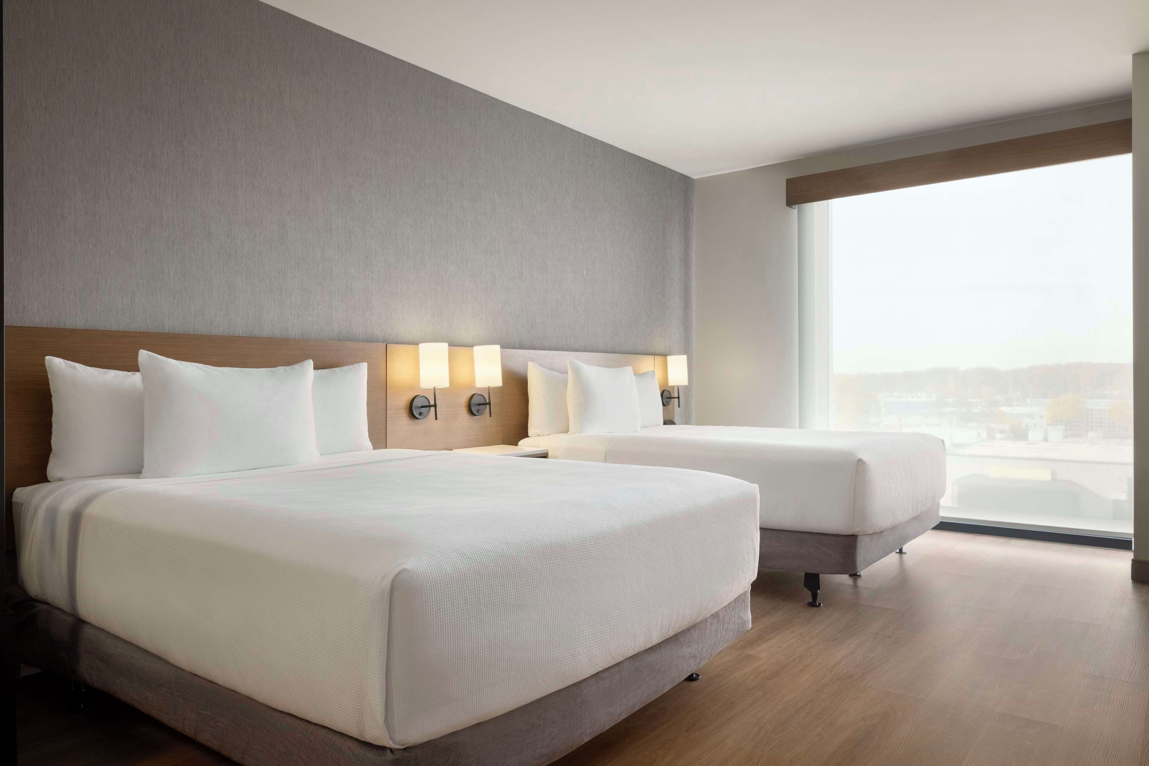 Une chambre d’hôtel avec deux lits, une grande fenêtre et une vue sur la ville.