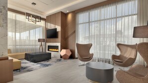 Un salon moderne doté d’une cheminée, de sièges confortables et de grandes fenêtres.
