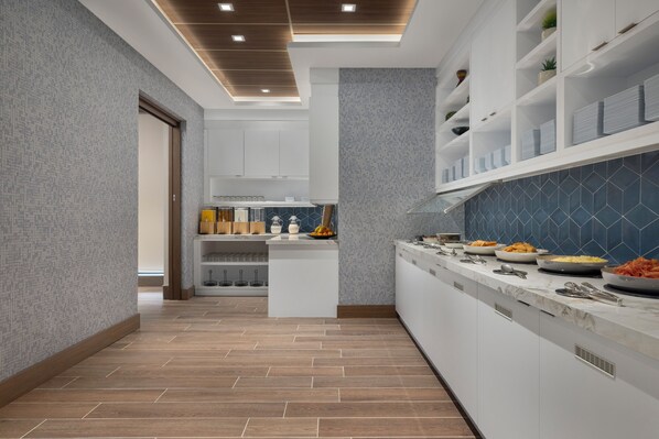 Une cuisine moderne dotée d’un îlot central, de meubles blancs et d’un revêtement mural bleu.