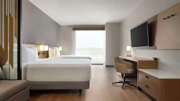 A hotel room with a large bed, a desk, a TV, and a view of the city.