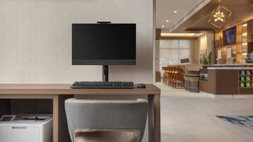 Un moderno vestíbulo de hotel con un mostrador de recepción de madera, un televisor de pantalla plana, un teclado, un ratón y una impresora.
