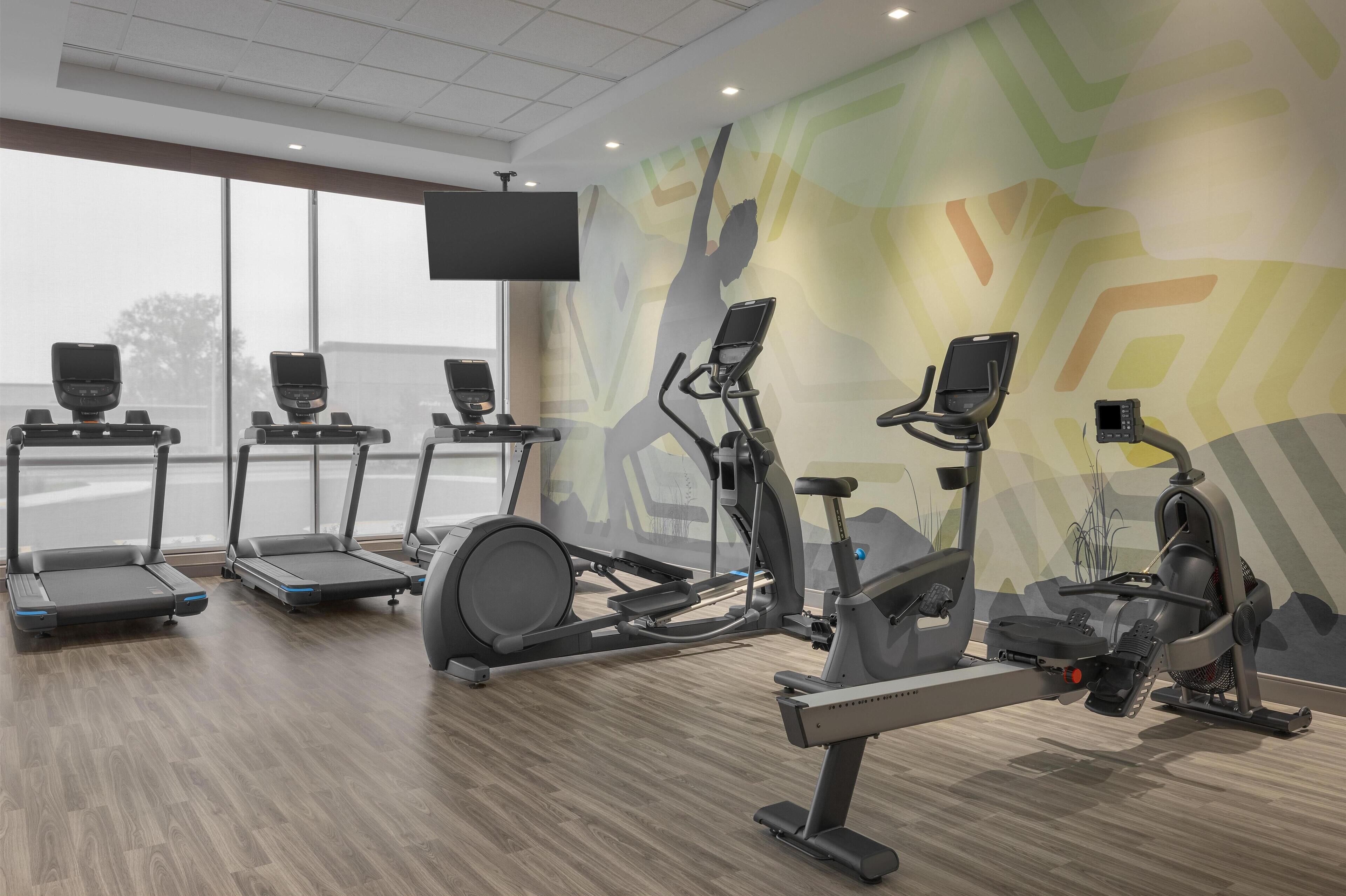 A gym with treadmills, elliptical machines, and stationary bikes.