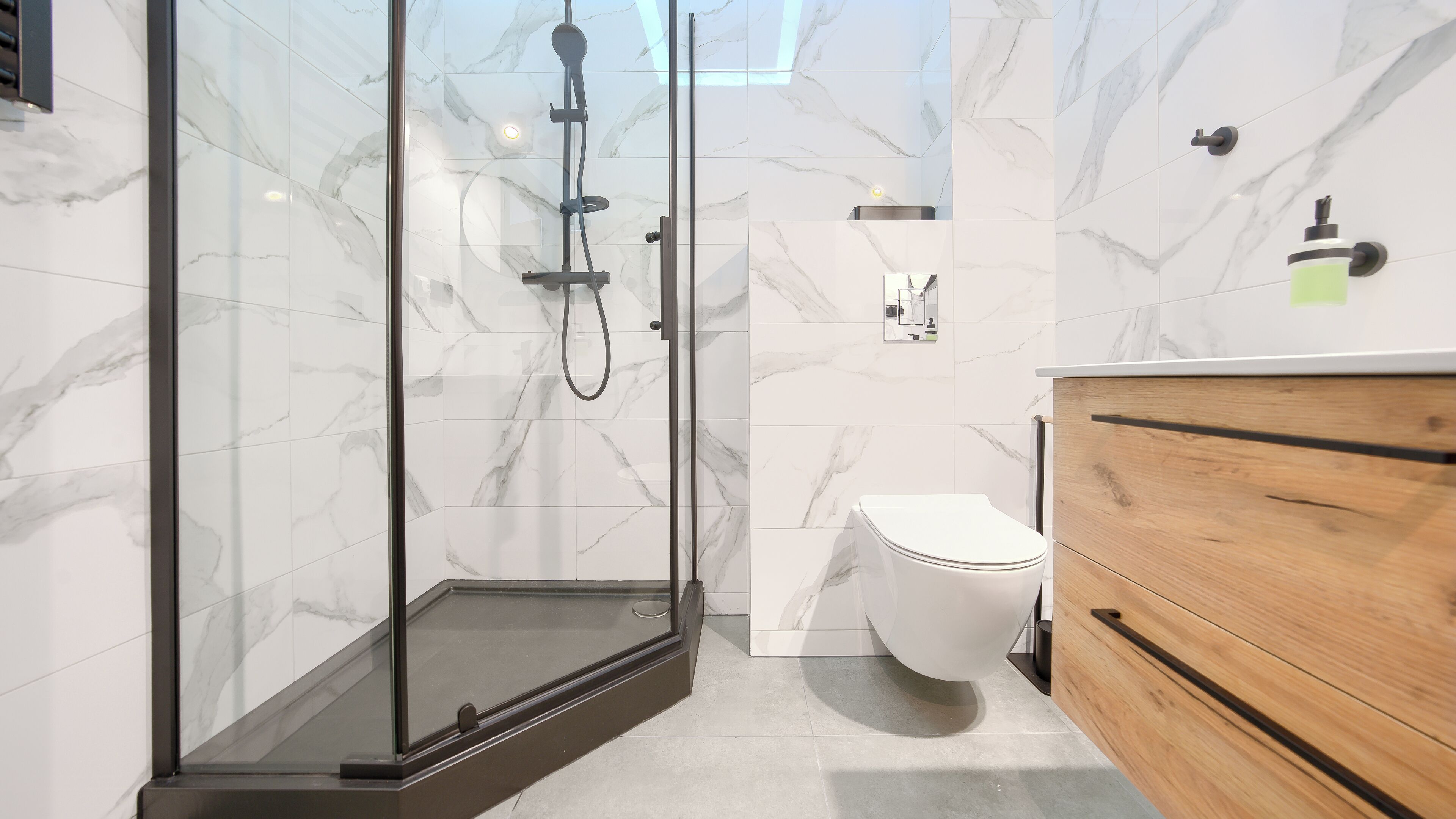 Une salle de bain moderne avec une douche à parois de verre, des toilettes blanches et un meuble-lavabo en bois.