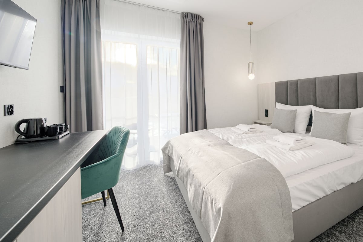 A hotel room with a bed, a desk, a chair, and a window with curtains.