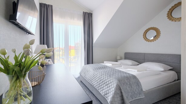 A modern bedroom with a bed, a desk, and a view of the outdoors. - Apartamenty Sun & Snow Na Spokojnej (Kolobrzeg)