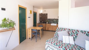 Un espacio habitable compacto con kitchenette, comedor y sofá con tapicería estampada.