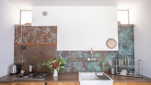 Una cocina moderna con estufa de acero inoxidable, pileta blanca y muebles de madera.