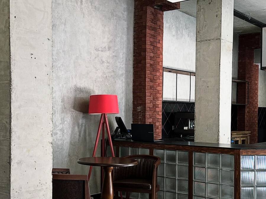 A bar area with a checkered floor, a red lamp, and a brick column.