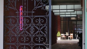 A hotel entrance with a wrought iron gate, a neon sign reading "Station 22", and a seating area visible through the glass doors. - Station22 (Batumi)