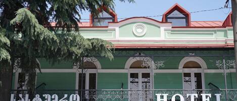 A green building with a red roof and a sign that reads "HOTEL".