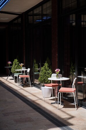 An outdoor seating area with tables and chairs, potted plants, and a brick wall. - Station22 (Batumi)