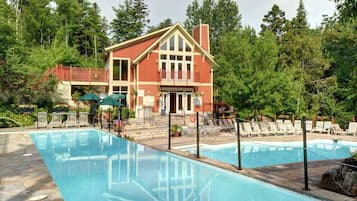 Un bâtiment à deux étages avec une piscine, entouré d’arbres.