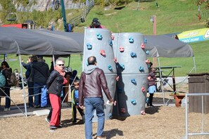 A climbing wall with multiple holds and a shaded area with a tent.