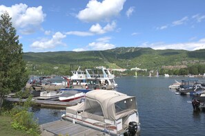 Ein Yachthafen mit verschiedenen Schiffen, darunter ein weißes Motorboot und ein größeres Schiff mit überdachter Deckfläche.