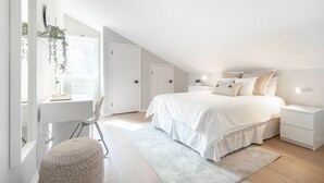 A modern bedroom with a large bed, bedside tables, a desk, and a chair. - Bright & Modern Lac Tremblant Condo + Views (Mont-Tremblant)