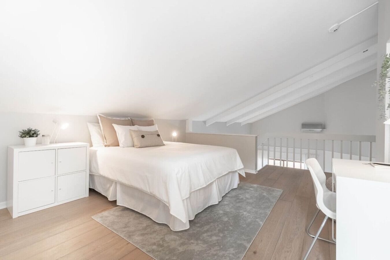 A modern bedroom with a bed, bedside table, and a desk area.