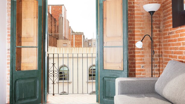 An open door leading to a courtyard with a view of buildings, a lamp, and a sofa inside. - Amazing Classic Apartment by Sagrada Familia With Balcony an (Barcelona)