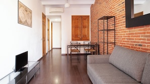 A modern living room with a sofa, TV, and a dining area with chairs and a table.