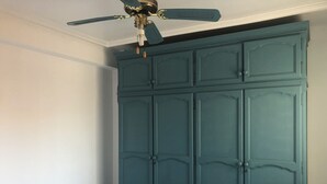 A bedroom with a teal-colored wardrobe, a ceiling fan, and a white bed. - Almería Centro (Almería)