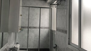 A modern bathroom with a glass-enclosed shower, a marble sink, and a large window providing natural light. - Almería Centro (Almería)