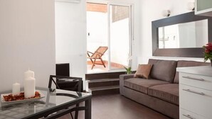 A modern living room with a glass dining table, a sofa, and a white cabinet.