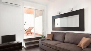 A modern living room with a sofa, a flat-screen TV, and a large mirror on the wall.